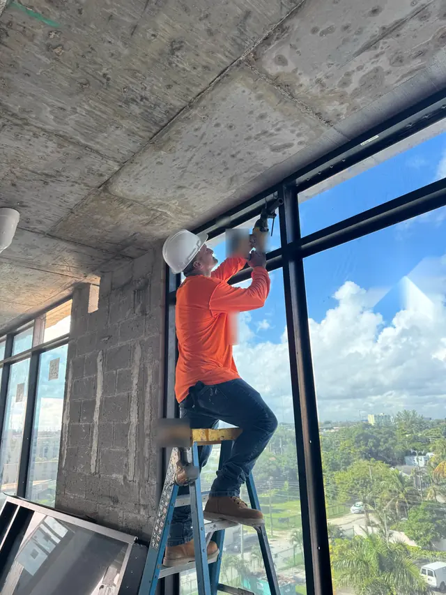 Mora Glass Windows installer adjusting an impact window on an upper floor